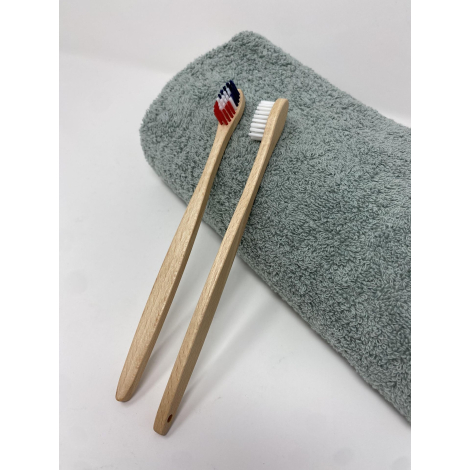 Deux brosses à dents en bois clair côte à côte sur une serviette textile vert clair, sans personnalisation visible