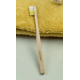 Brosse à dents pour enfant en bois clair présentée sur serviette textile jaune, manche rectiligne avec poils clairs et colorés, Brosse à dents pour enfant en bois clair présentée sur serviette textile jaune, manche rectiligne avec poils clairs et colorés,