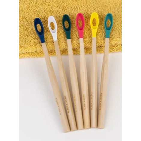 Brosses à dents en bois clair alignées sur serviette textile jaune, vues de face avec têtes colorées différentes, marquage visib