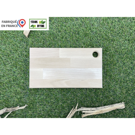 Planche à découper rectangulaire en bois clair taille M, vue de face sur fond végétal, avec trou circulaire dans un angle, surfa