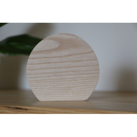 Trophée en bois clair de forme semi-circulaire, photographié de face sur une étagère, surface plane avec veines du bois visibles