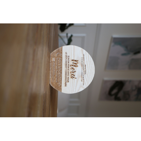 Trophée en bois clair de forme semi-circulaire, photographié en situation sur surface en bois, personnalisation visible sur la f