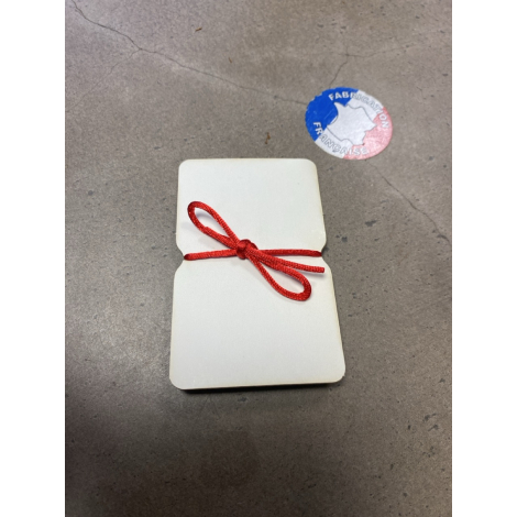 racelet en bois présenté sur support cartonné neutre, maintenu par un cordon rouge noué, posé sur surface minérale, produit emba