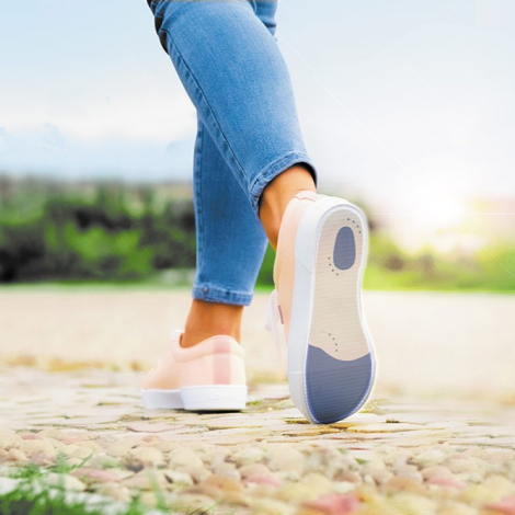 Personne en mouvement vue de dos, marchant sur sol pavé, semelle extérieure de chaussure visible, usage en extérieur.