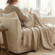 Plaid beige clair en coton biologique posé sur les jambes en intérieur