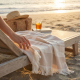 Fouta beige et blanche à rayures posée sur transat en bois sur la plage