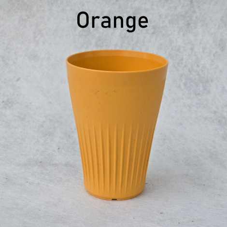 Gobelets réutilisables JoJo en plusieurs coloris disposés en extérieur sur herbe en situation événementielle, sans marquage visi