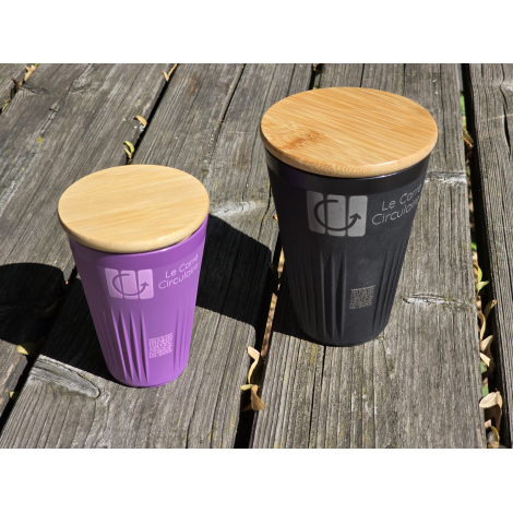 Deux gobelets avec couvercle posés sur une surface en bois, l’un violet et l’autre noir, avec personnalisation visible sur la fa