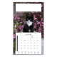 Calendrier illustré d’un chat noir et blanc devant une floraison rose abondante.