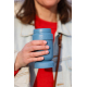 Gros plan sur une personne tenant à la main un mug réutilisable bleu ouvert, à corps rainuré, avec son couvercle placé sous le m Gros plan sur une personne tenant à la main un mug réutilisable bleu ouvert, à corps rainuré, avec son couvercle placé sous le m