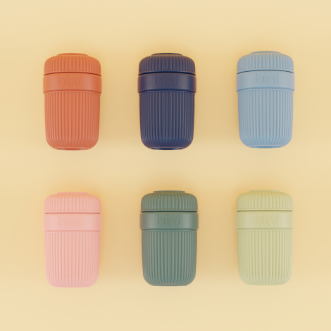 Mug réutilisable bleu à corps rainuré, ouvert et muni d’une paille métallique coudée, posé sur une nappe à carreaux lors d’un pi