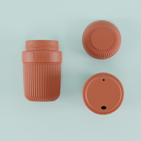 Composition présentant un mug réutilisable terracotta ouvert, avec corps rainuré et marquage visible en relief, accompagné de so