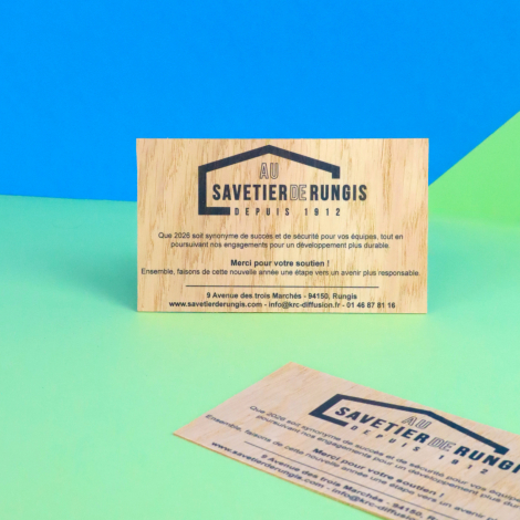 Cartes de vœux en bois personnalisées avec logo et texte, mises en scène sur un fond bleu et vert.