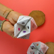 Cocottes en papier ensemencé personnalisées utilisées comme jeu interactif, présentées dans les mains sur fond rouge.