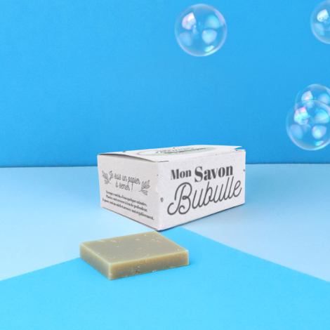 Savon solide et sa boîte en papier ensemencé personnalisée, mis en scène sur fond bleu avec des bulles.