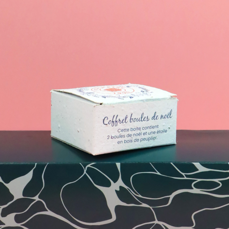Boîte en papier ensemencé personnalisée pour coffret de décorations de Noël, présentée sur fond rose.