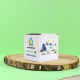 Boîte cube personnalisée en carton ensemencé, imprimée en quadrichromie et présentée sur une rondelle de bois sur fond vert.