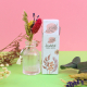 Étui personnalisé en papier à semer accompagné d’un petit bouquet de fleurs séchées placé dans un vase, sur décor rose et vert. Étui personnalisé en papier à semer accompagné d’un petit bouquet de fleurs séchées placé dans un vase, sur décor rose et vert.
